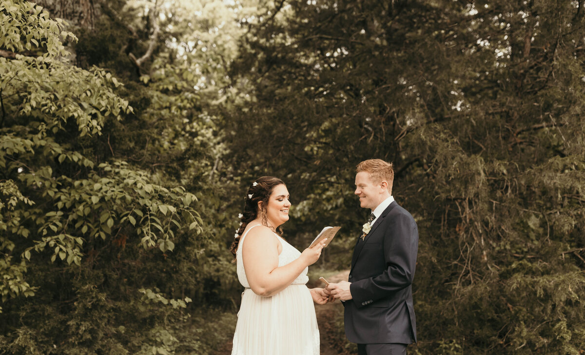 couple reciting vows in woods during summer camp elopement