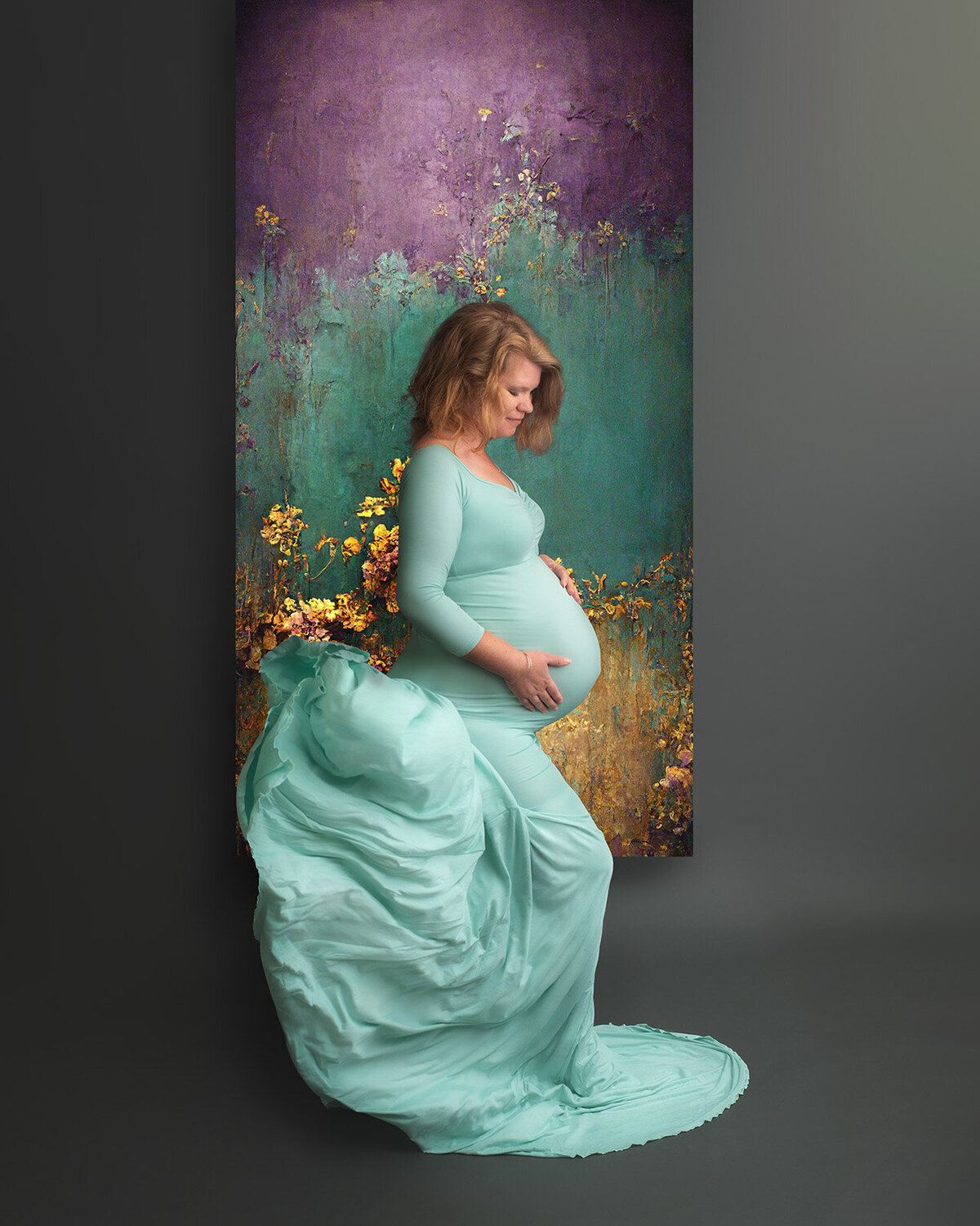 pregnant woman in seafoam gown with gold, blue, and purple backdrop at st. louis maternity session
