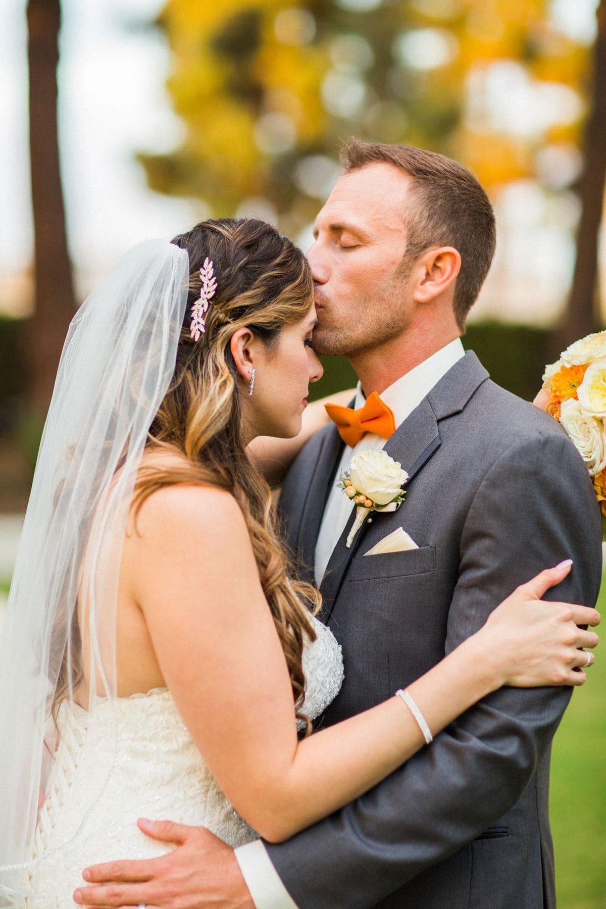 Tender moment as Groom kisses his Bride's forehead while embracing each other