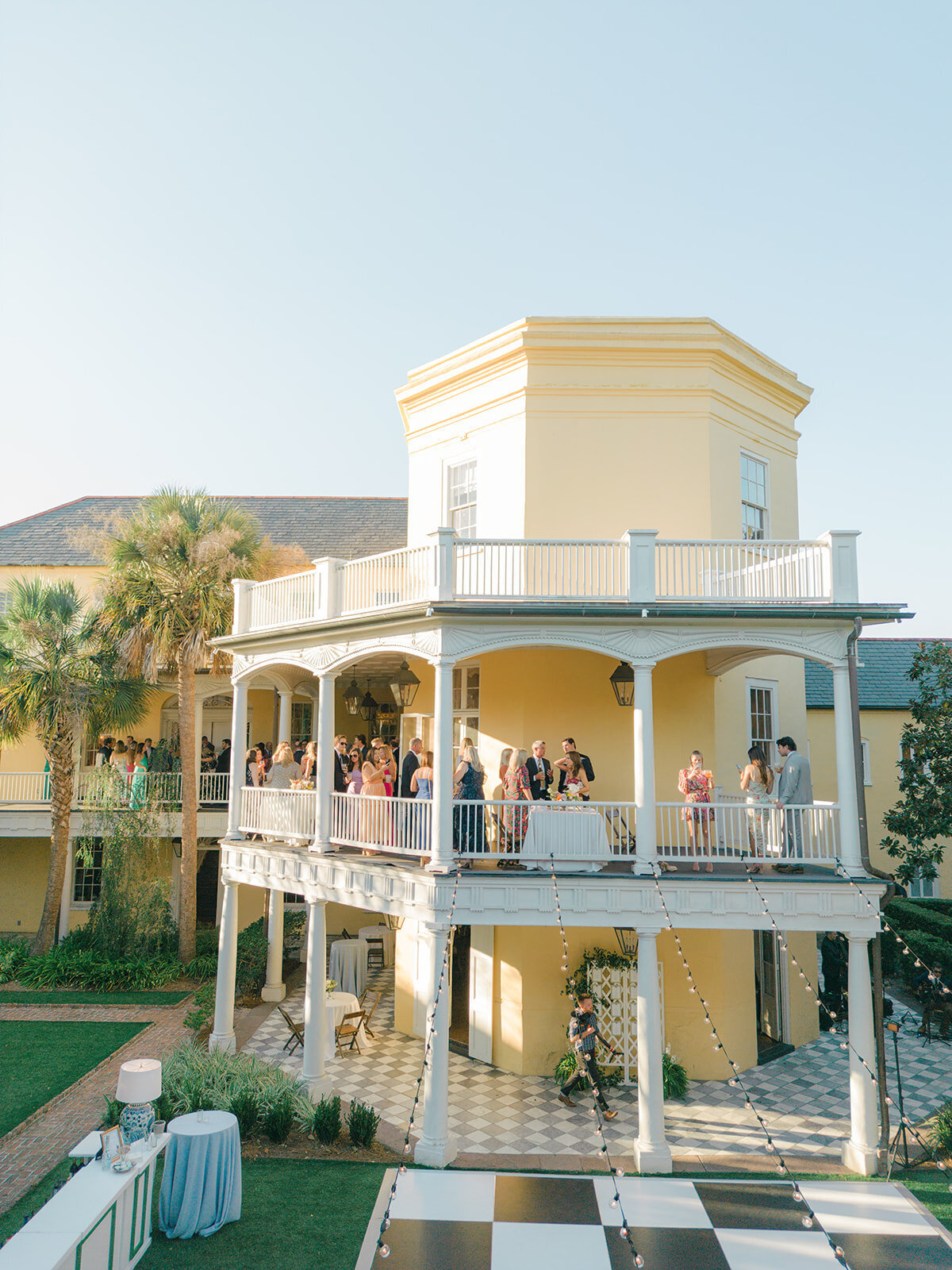 Cocktail hour on the grand porches of William Aiken House. Sunset light hits the house as guests enjoy the evening at fall wedding in downtown Charleston.