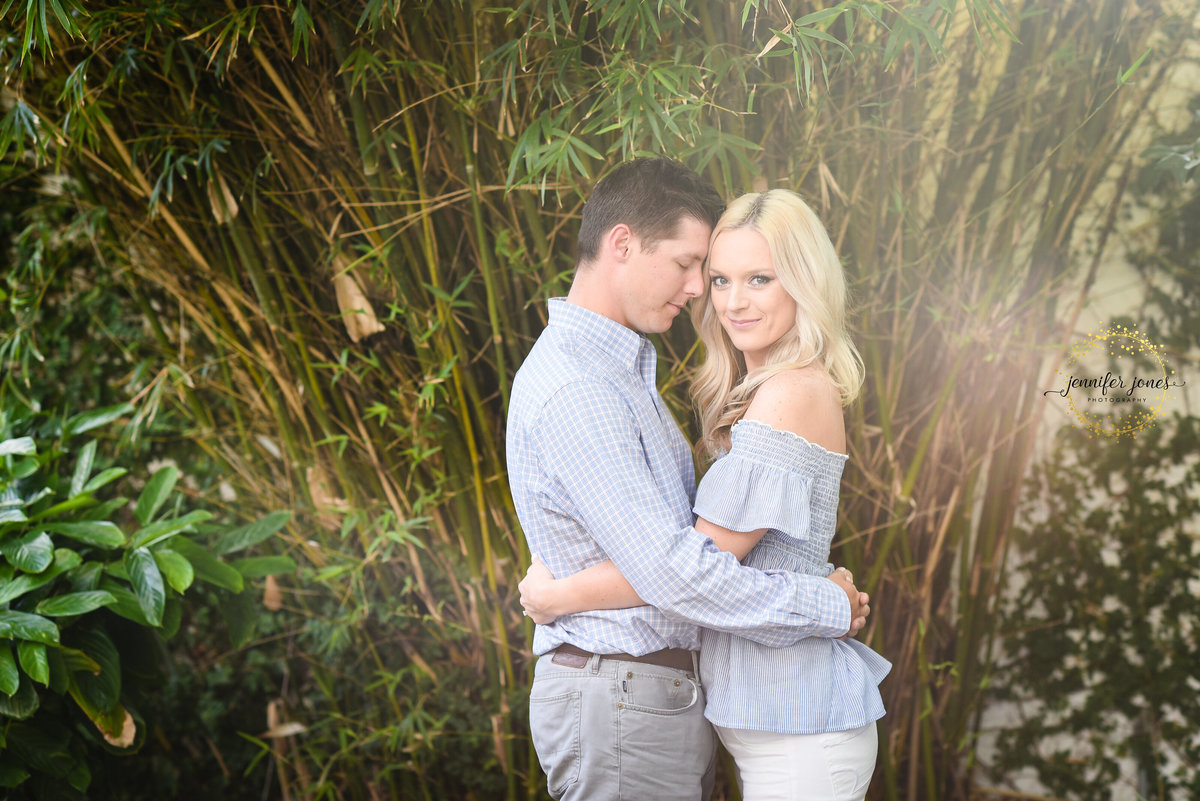 Beautiful Mississippi Engagement Photography: couple embraces in front of sunlit bamboo at Mary Mahoney's in Biloxi MS