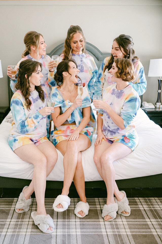 BrideBridesmaids in robes laughing together and bridesmaids getting ready