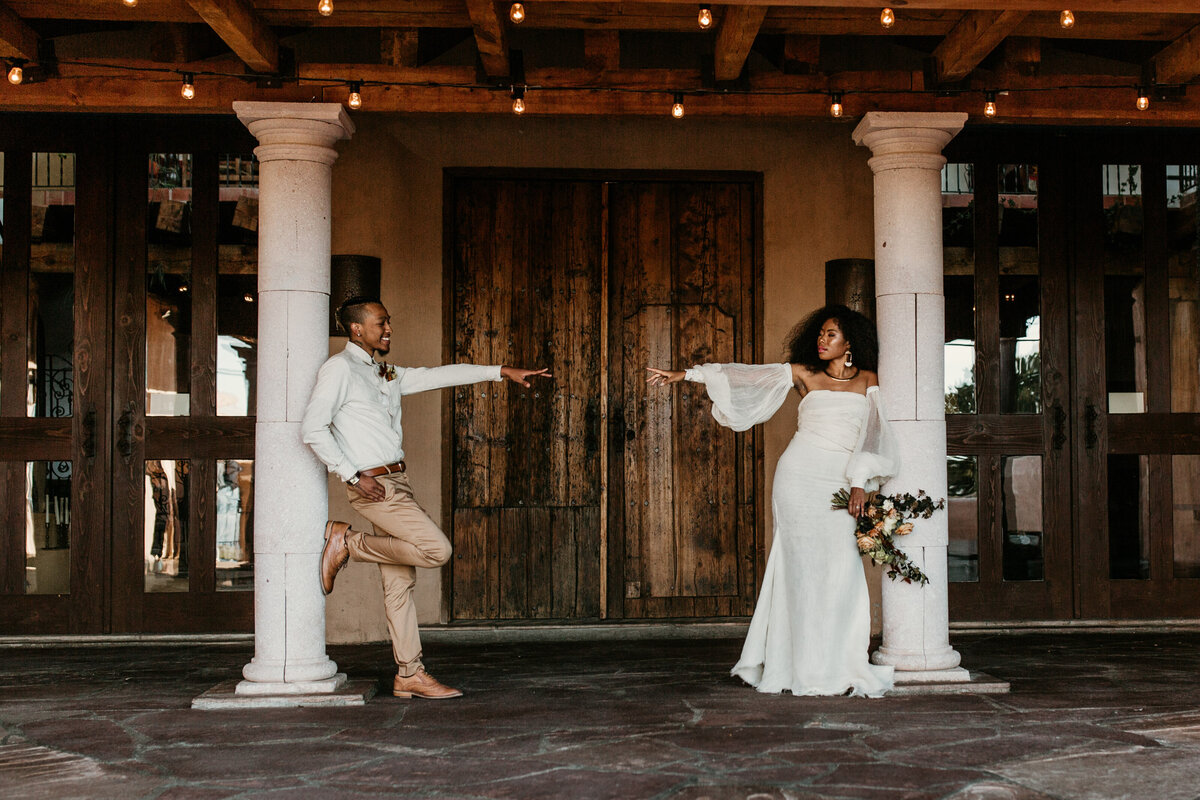 bride and groom  standing against a pillar