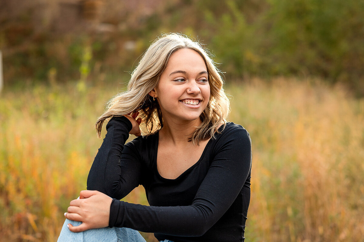 A senior girl smiles as she looks off in the distance during her photo session.