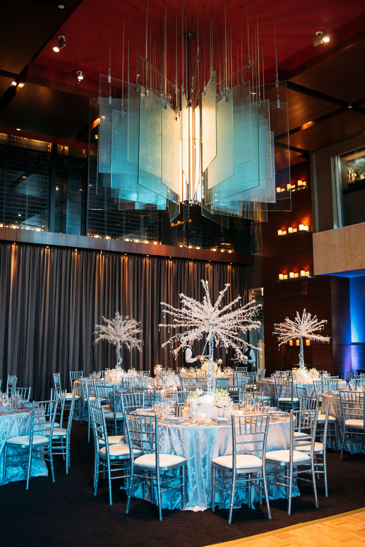 Elegant wedding reception in a hall with dinner tables, chairs and grand chandeliers