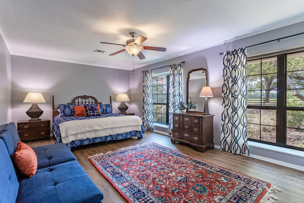 Large bedroom with comfortable bedding, sofa and plenty of natural light in this 5-bedroom, 4-bathroom vacation rental house for 16+ guests with pool, free wifi, guesthouse and game room just 20 minutes away from downtown Waco, TX.