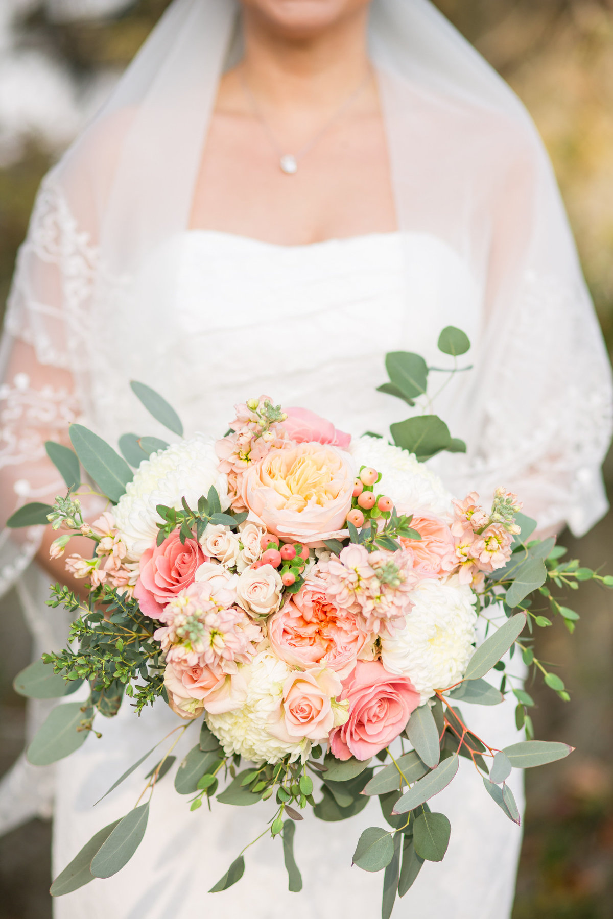 close up of bride holding a peach and pink bouquet of flowers