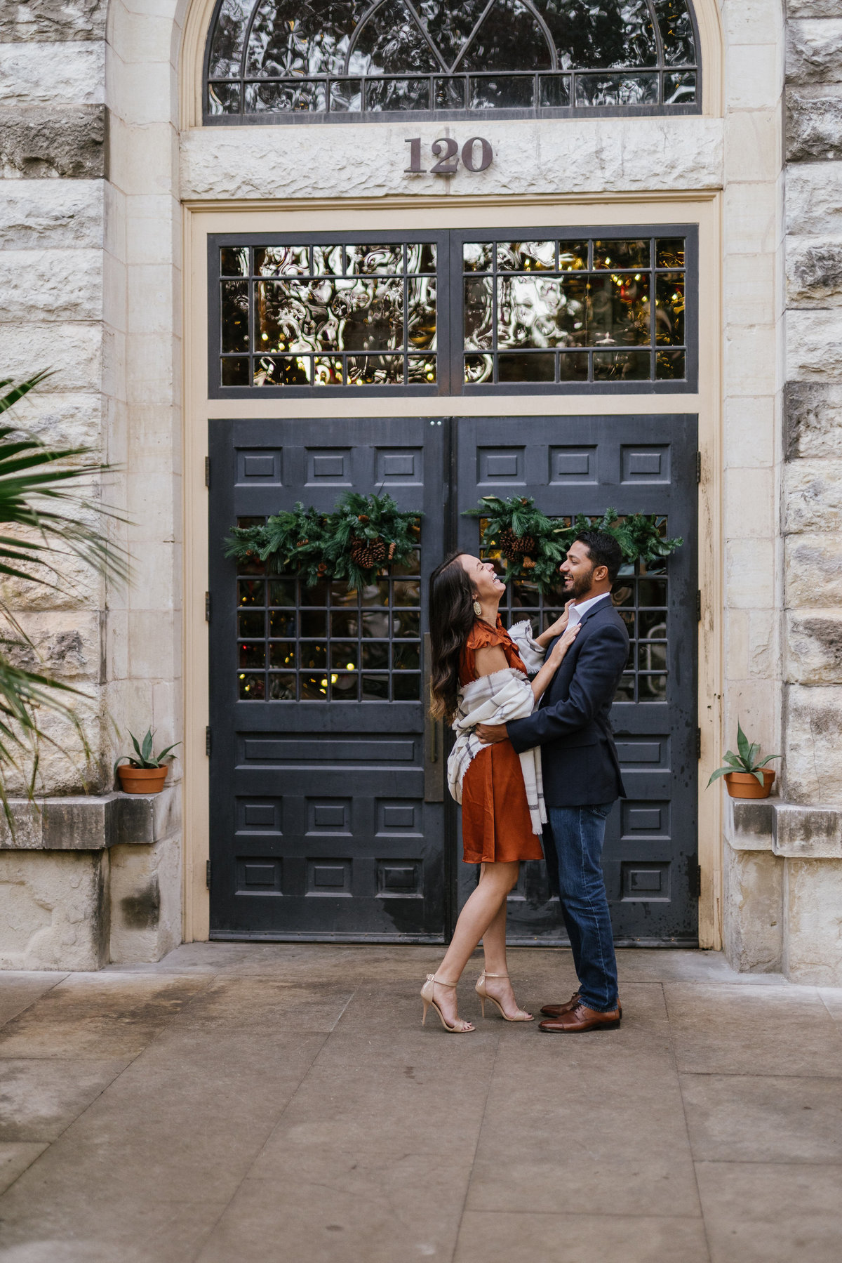 Engaged couple holding each other in front a door at the Hotel Emma at the Historic Pearl by the San Antonio River Walk.