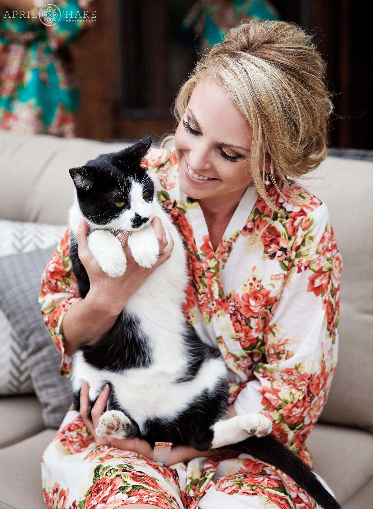 Bride in a floral robe snuggles her farm cat on her wedding day in Boulder Colorado