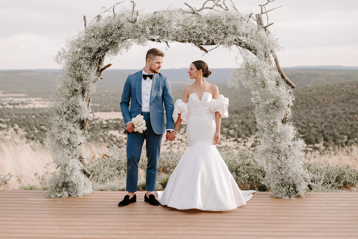 bride and groom holding hands under arch