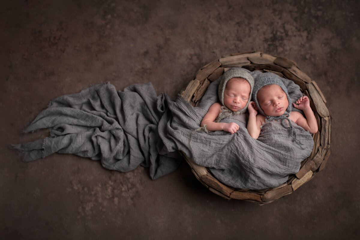 Wrapped newborn twin in a bucket captured by Laura King Photography