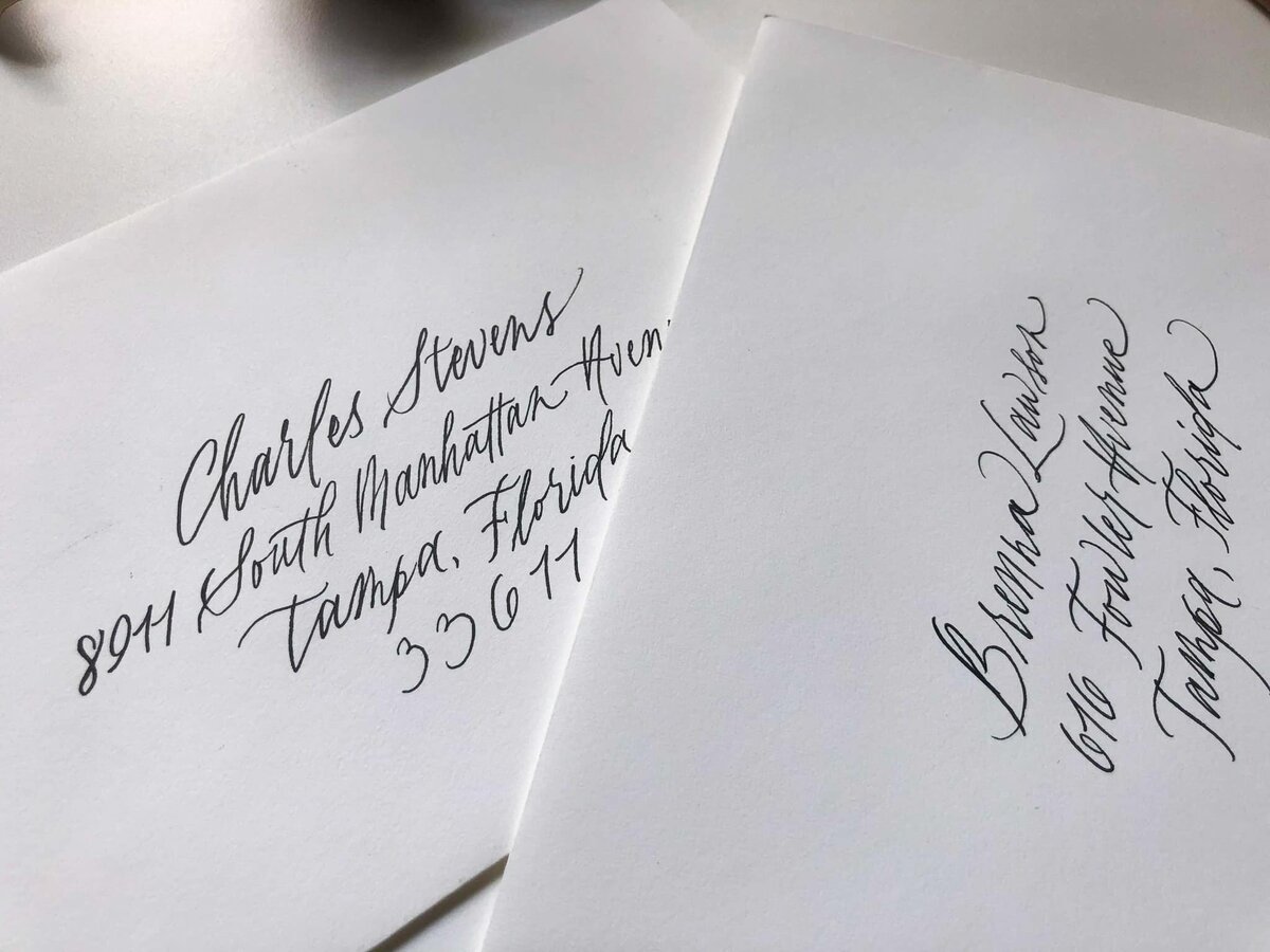 two calligraphy addressed white envelopes on a white table