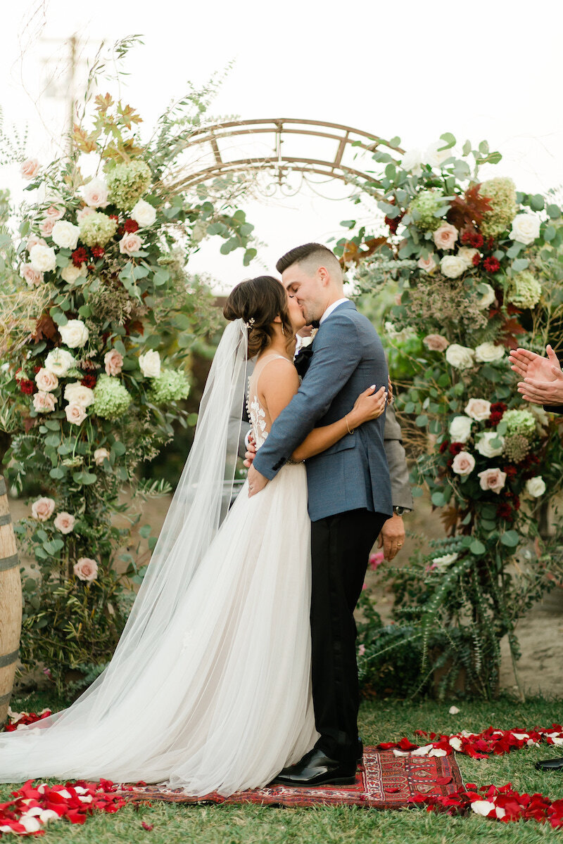 Bride and groom standing on a carpet in front of the arch