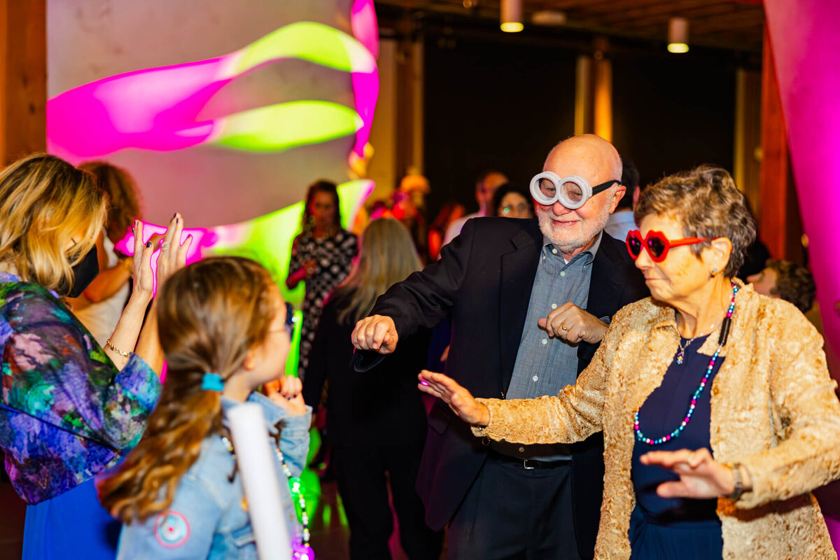 Grandparents dance on the dance floor in big colorful sunglasses