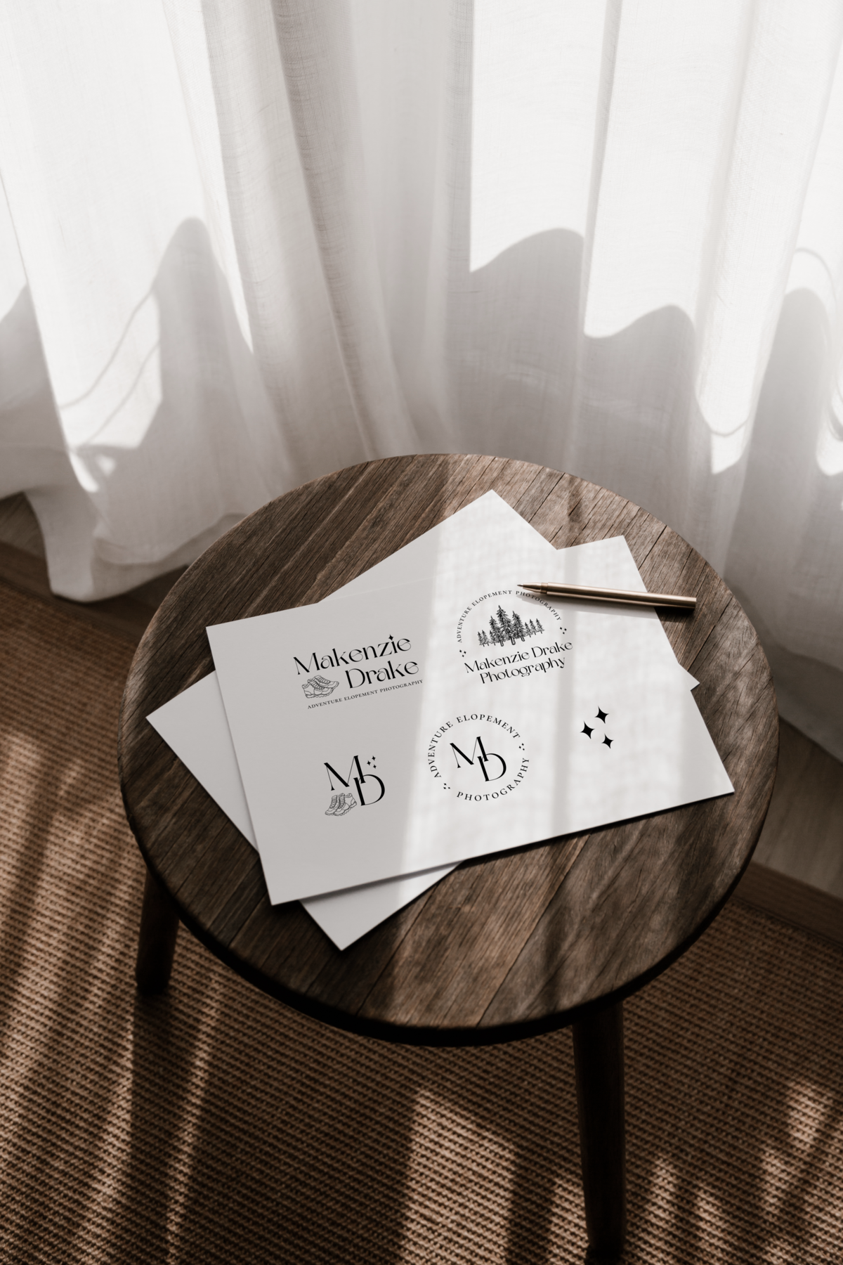 Papers with printed elopement photographer logos on paper lying on a table in the sunlight