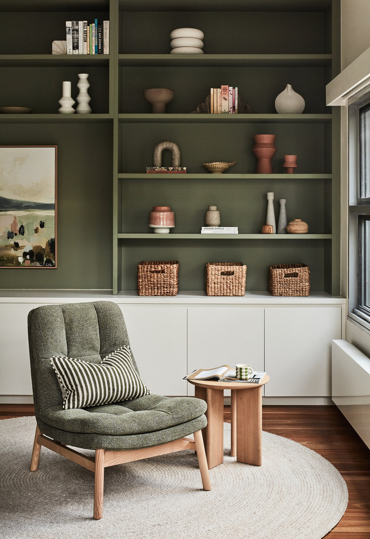 Melbourne interior design project featuring reading nook with green armchair, timber side table, and styled shelving.