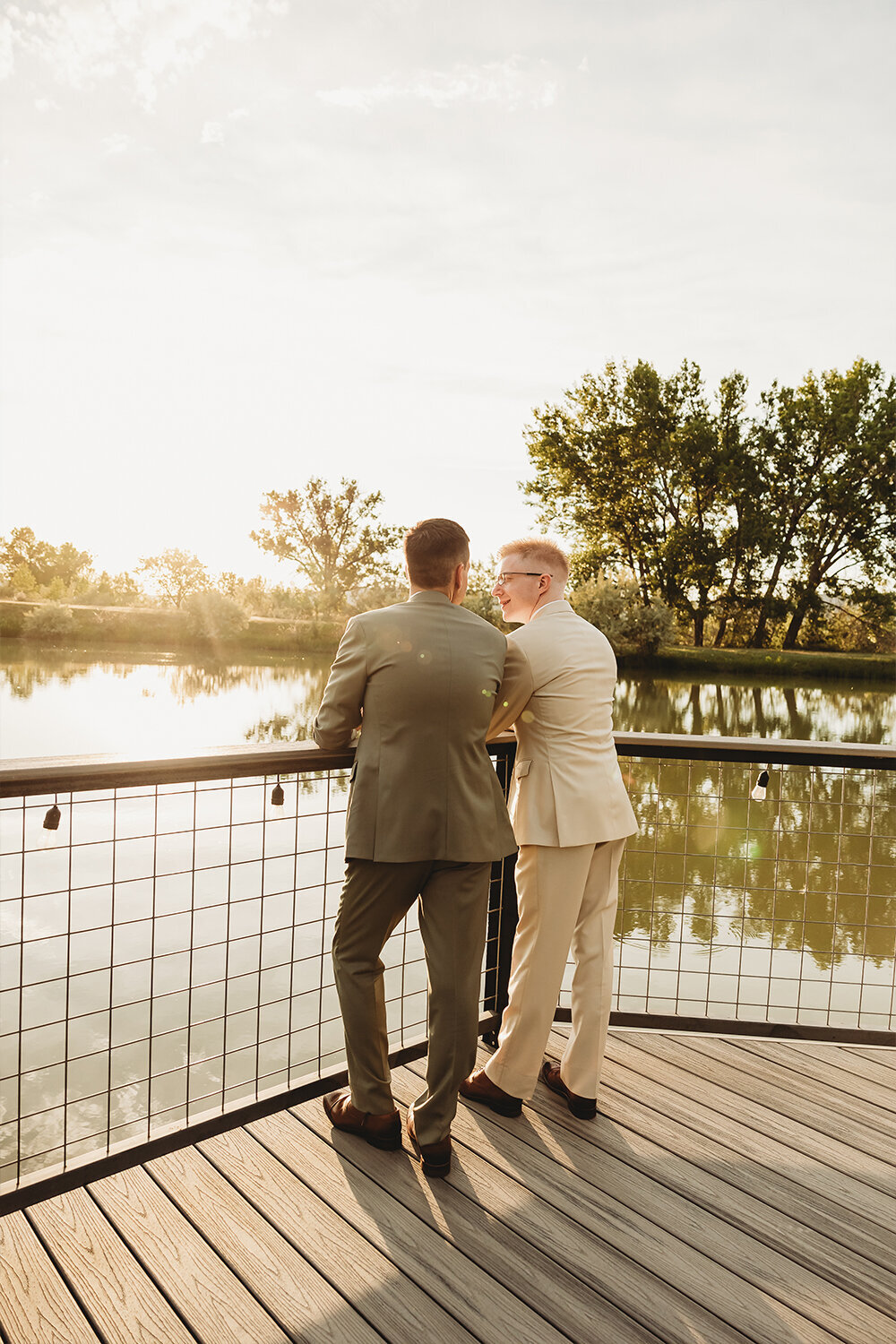 Grooms standing on dock overlooking water at Camelot Ranch.