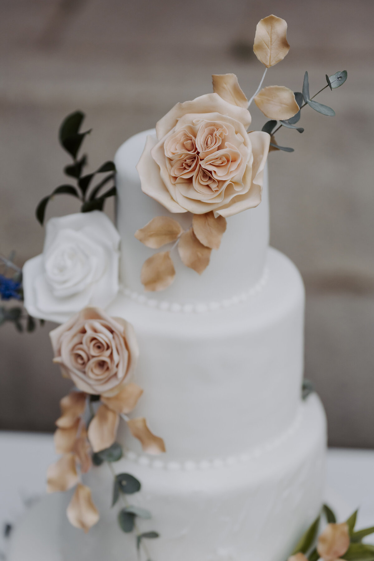 three-tier white wedding cake detailed with rose gold and white roses