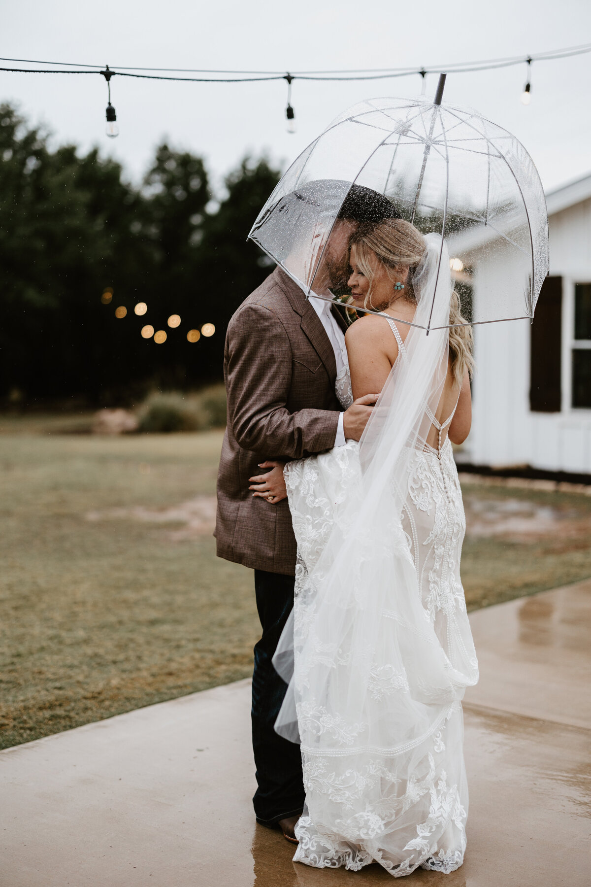 bride and groom in the rain with a clear umbrella