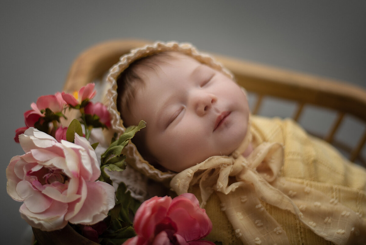newborn in yellow with pink flowers sleeping at newborn photo session