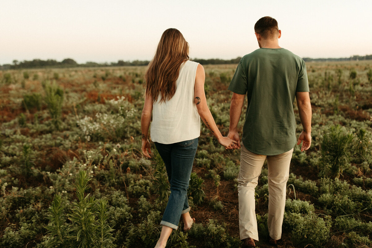 Couple holding hands and walking in a field