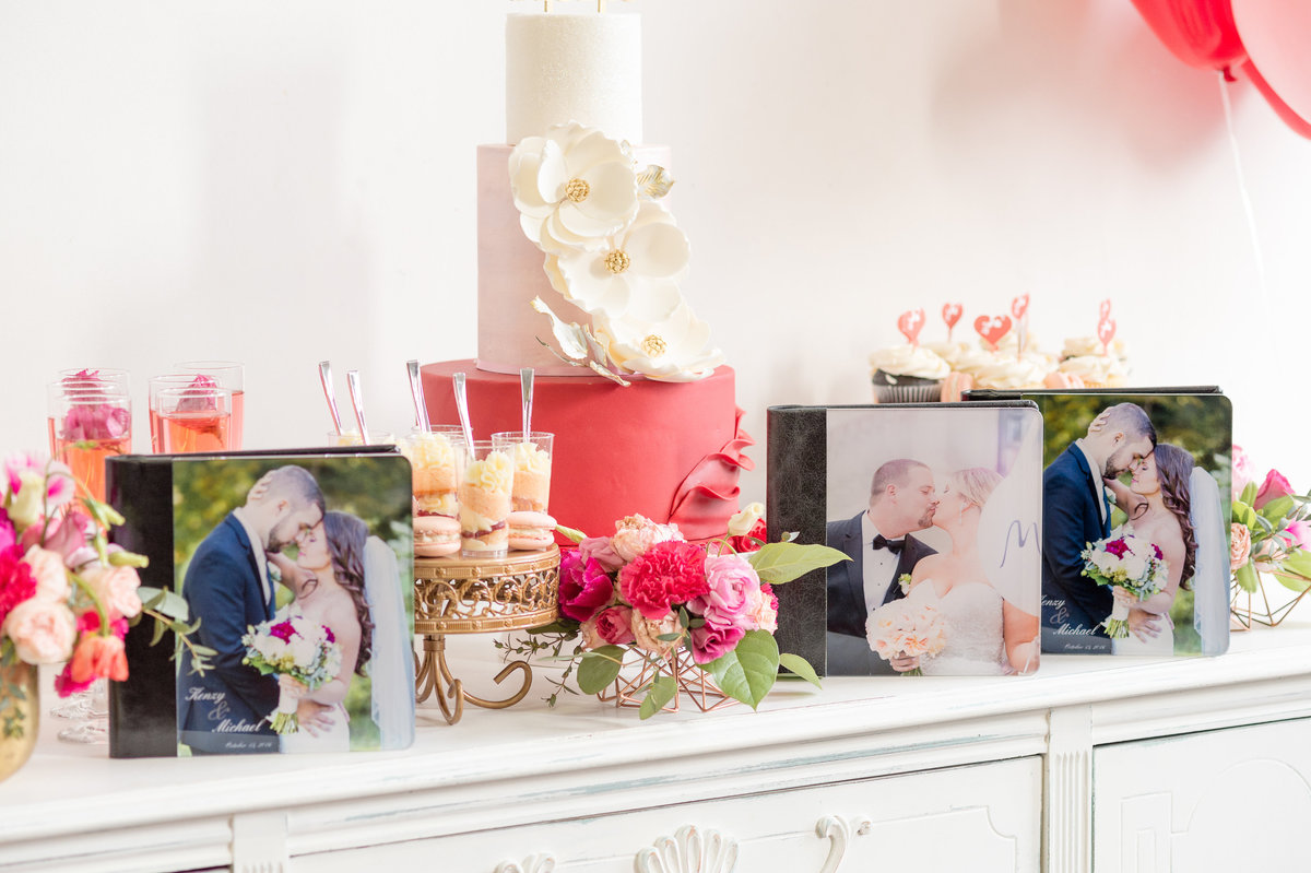 KSS Photography albums sit atop a counter amidst wedding cakes