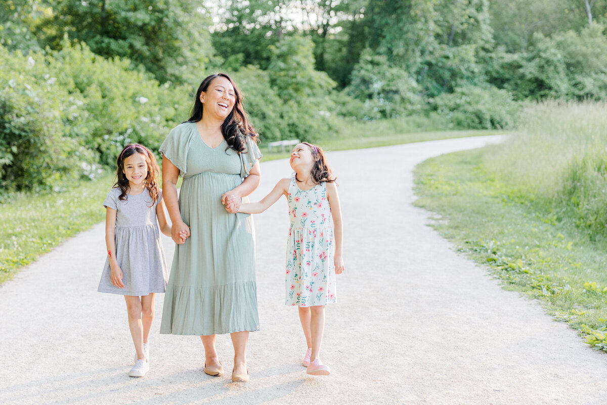 Mother and two daughters holding hands and laughing while they walk