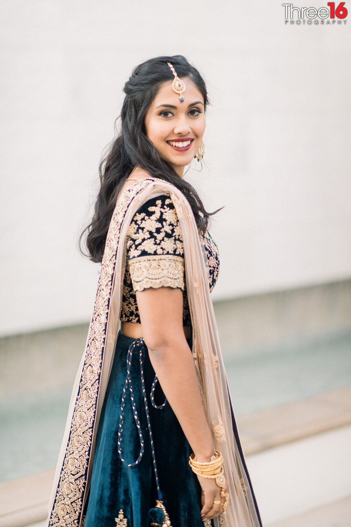 Beautiful Indian Bride wearing a traditional Indian wedding gown poses for photos with a big smile