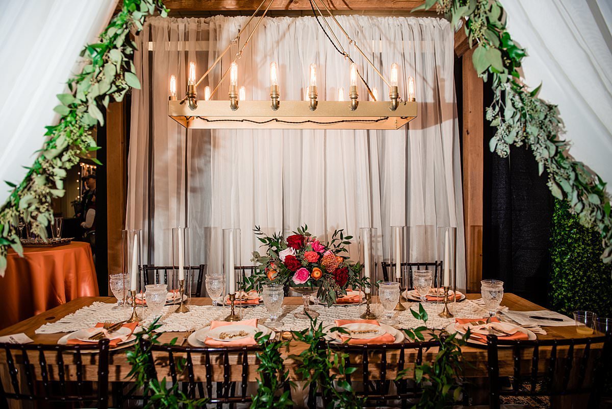 Peach, red and greenery filled elegant tablescape