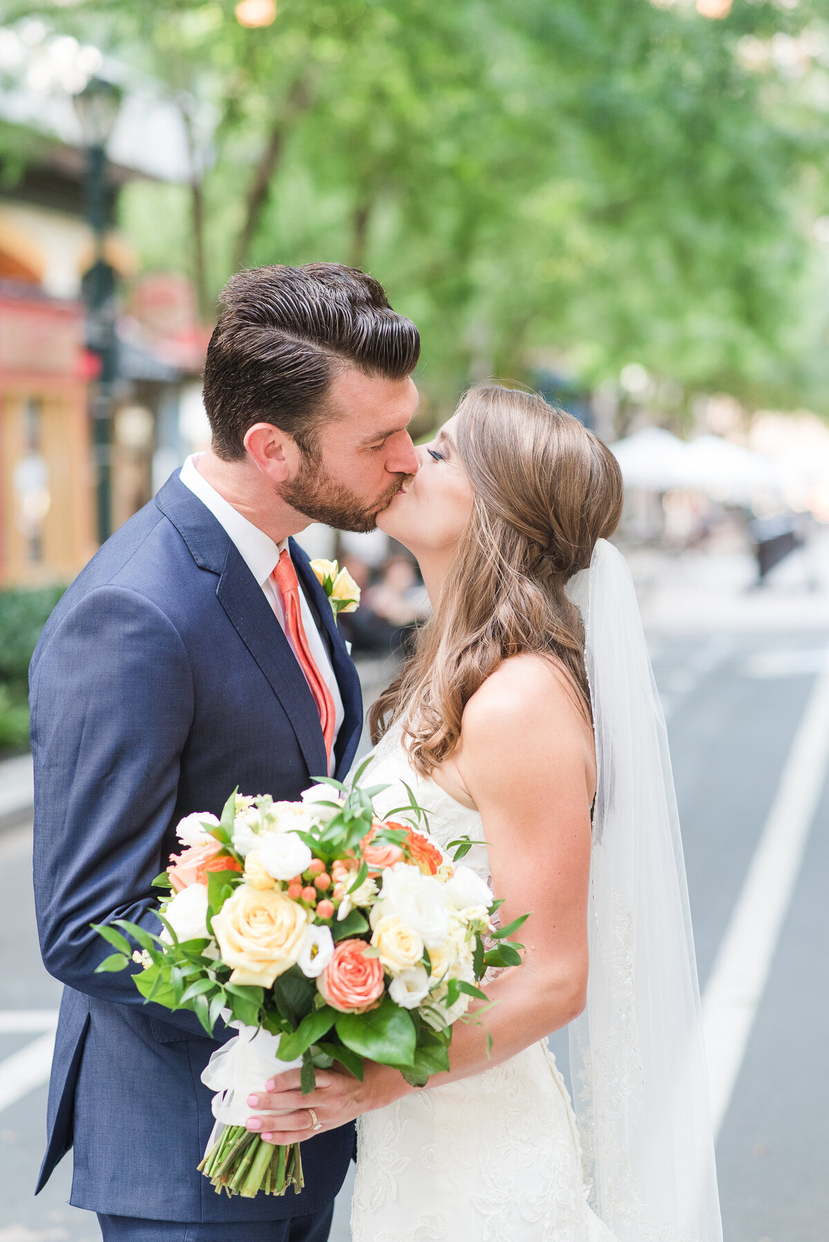 bride and groom kissing in city yellow and orange florals blue suit