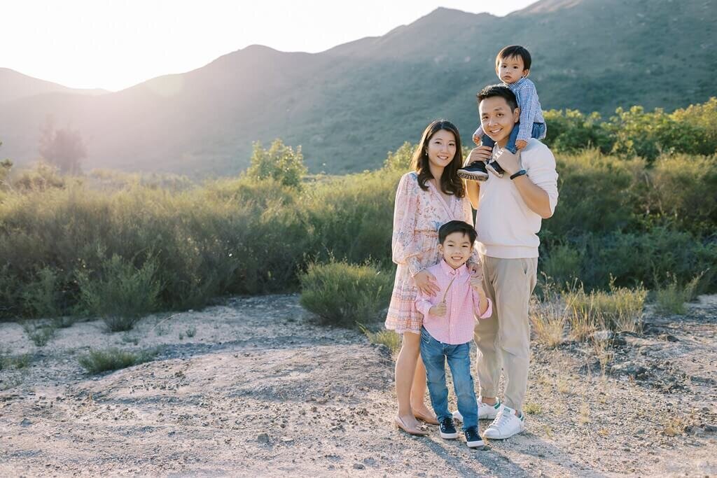 Family of four photo session with a serene mountainside backdrop.