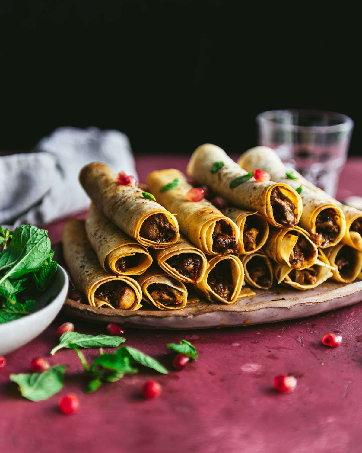 Omayah Atassi Dubai Food Photographer - Side-angle shot of musakhan (chicken sumac rolls) plated with a garnish of pomegranate and mint