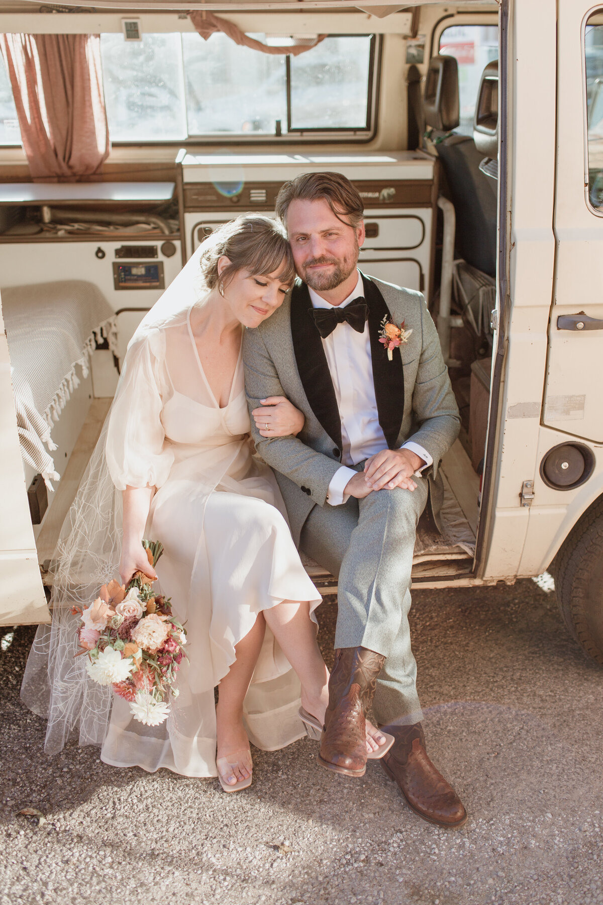 A cozy moment of a couple in wedding attire sitting in a VW Westfalia captured by Fort Worth wedding photographer, Megan Christine Studio