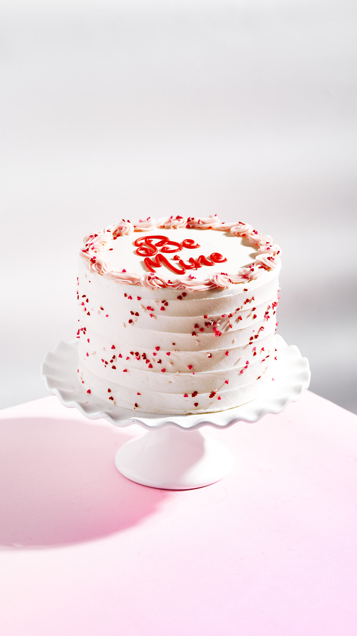 A tall round cake on a white stand.