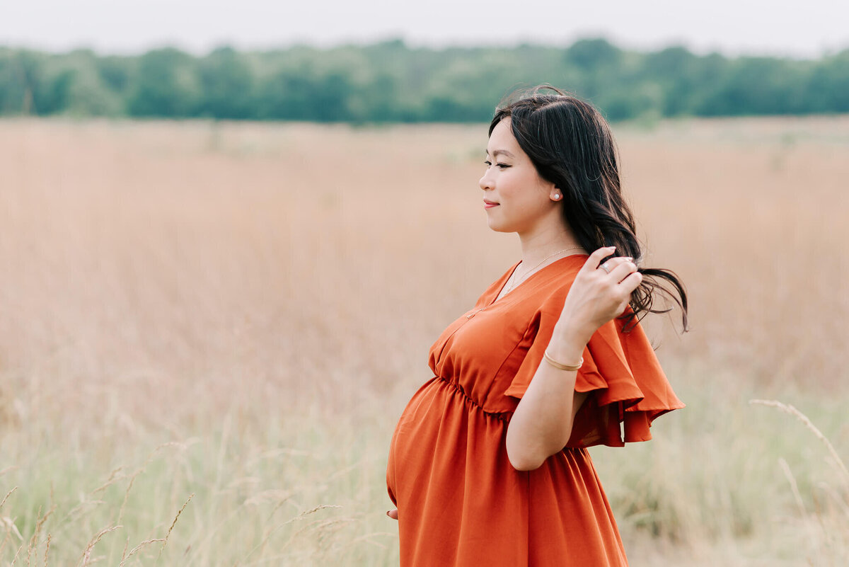 A beautiful mama-to-be holding her bump and gazing into the distance