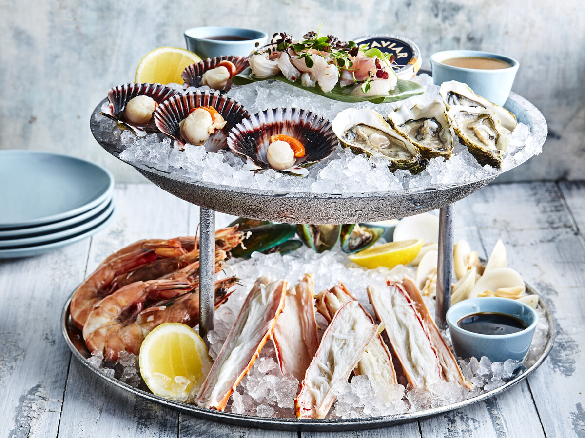 A two tiered plate with various types of seafood on them.