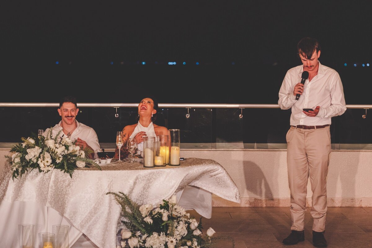 Bride laughing at joke during speech at wedding in Cancun
