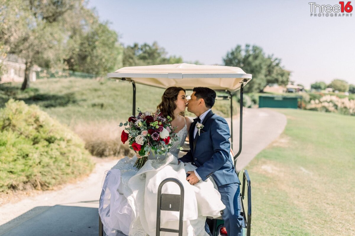 Bride and Groom share a sweet kiss while sitting on the back of a golf cart