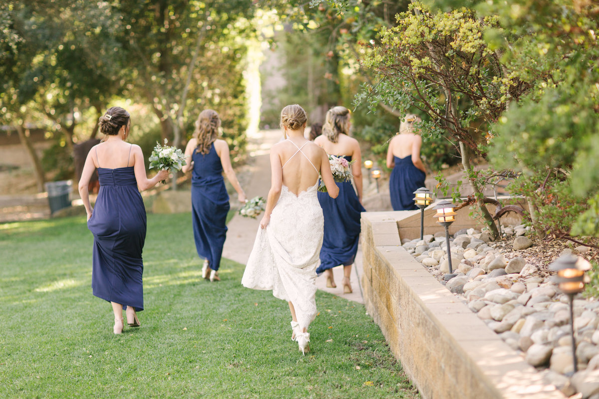 Bride and bridesmaids walk in vineyard at Firestone Winery wedding