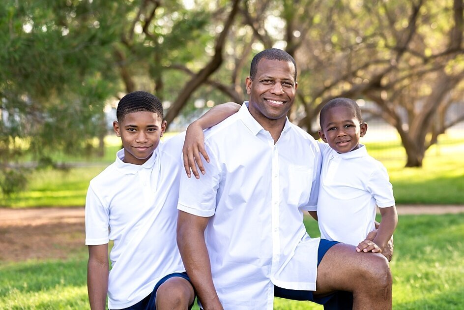 African American family of men all looking at the camera and wearing white  shirts and shorts