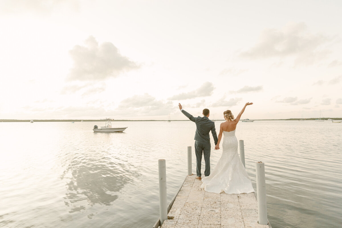 Bride and groom wave from the end of a dock