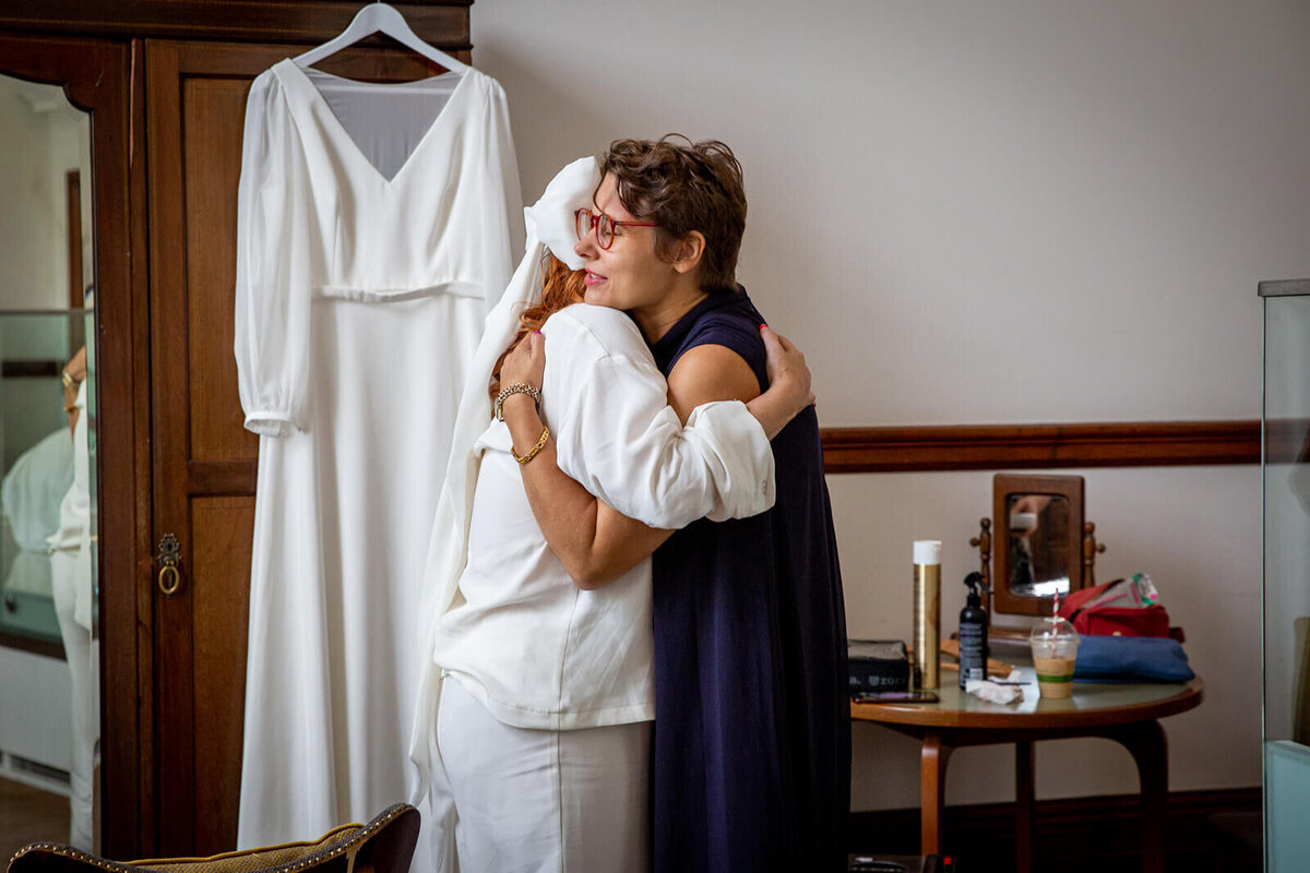 Bride hugging friend in town hall hotel bedroom