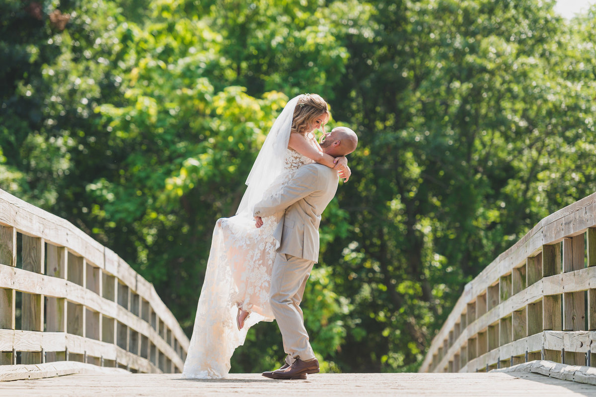 photo of groom holding up bride on bridge from wedding at Pavilion at Sunken Meadow