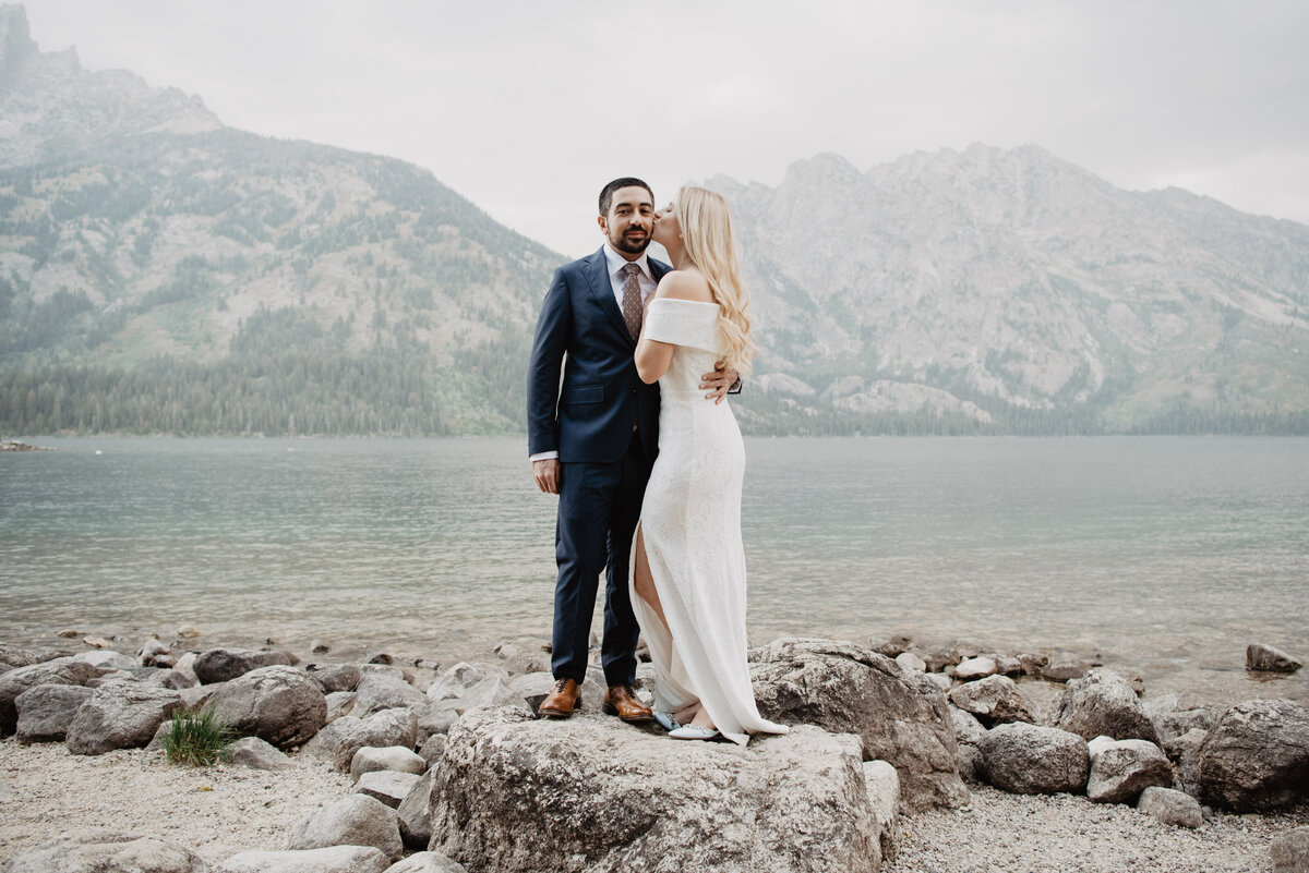 Photographers Jackson Hole capture bride kissing groom on rock