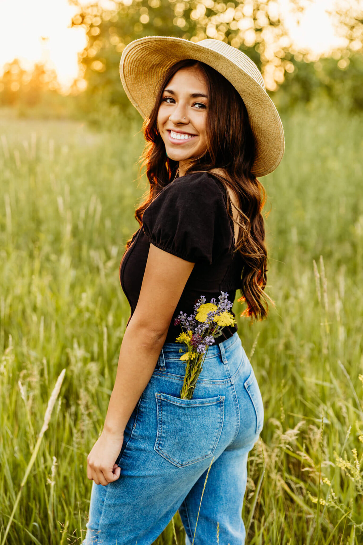beautiful young lady with flowers in her back pocket and a sunhat looking back