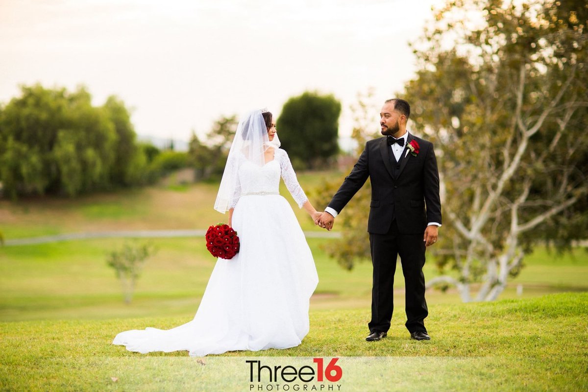 Bride and Groom hold hands while walking on the golf course at Royal Vista Golf Club