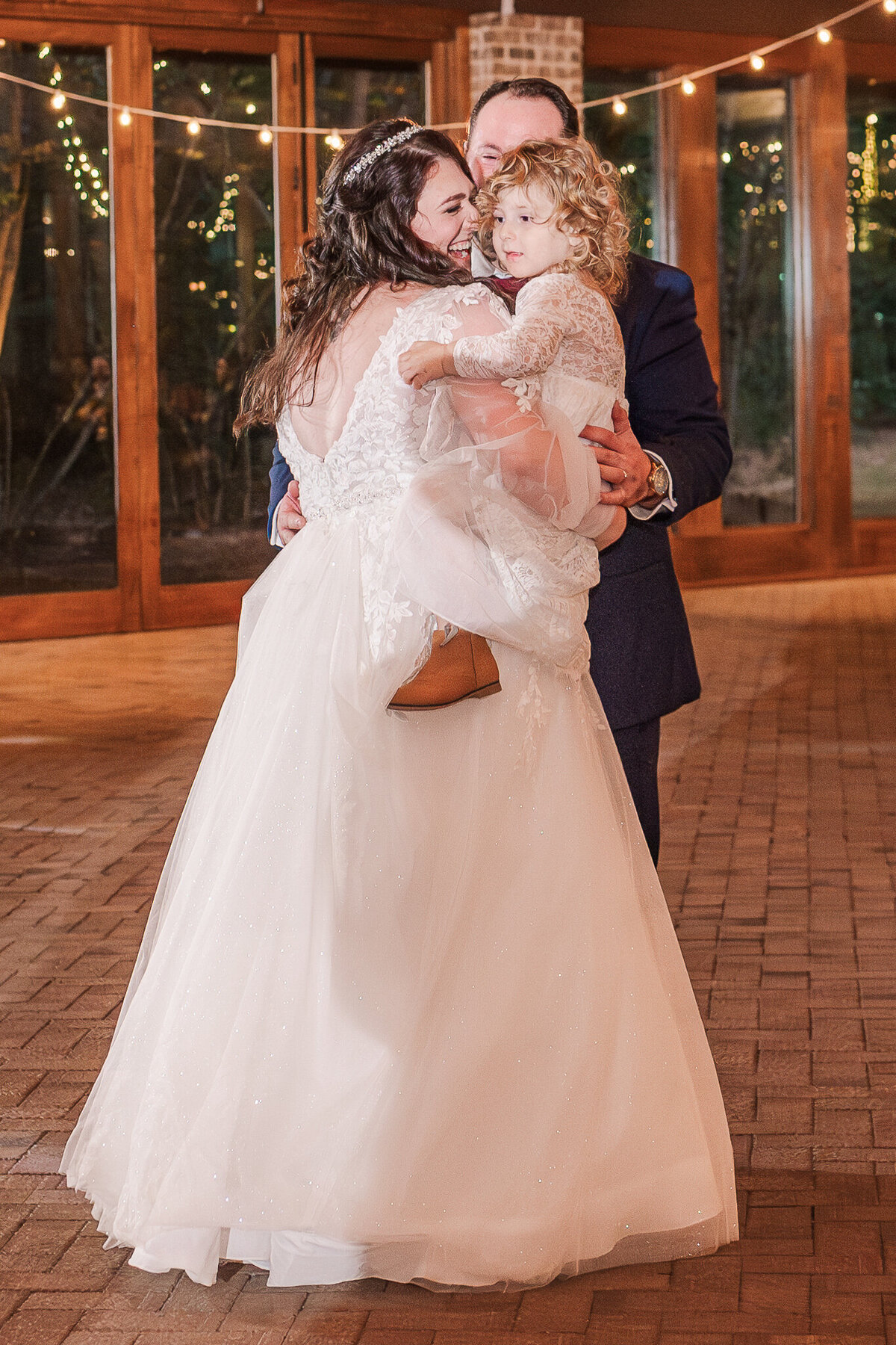 A bride and groom dancing while holding their daughter at their wedding reception enjoying their Raleigh wedding photos