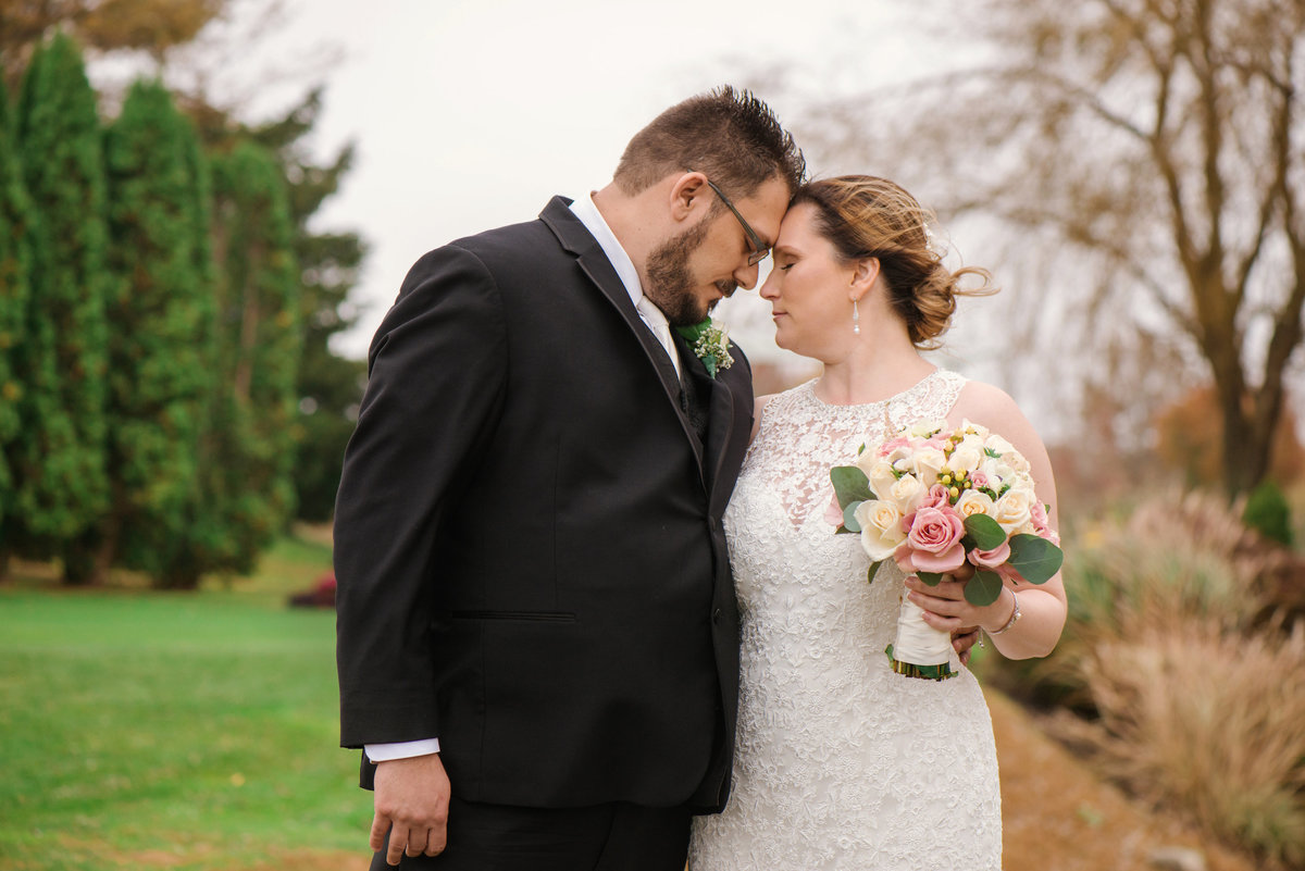 bride and groom touching foreheads on the golf course at Willow Creek Golf and Country Club