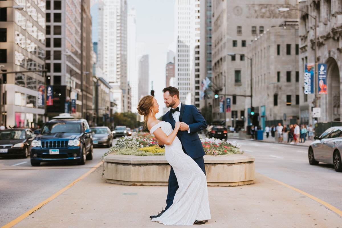 newlyweds dancing in city boulevard as traffic passes