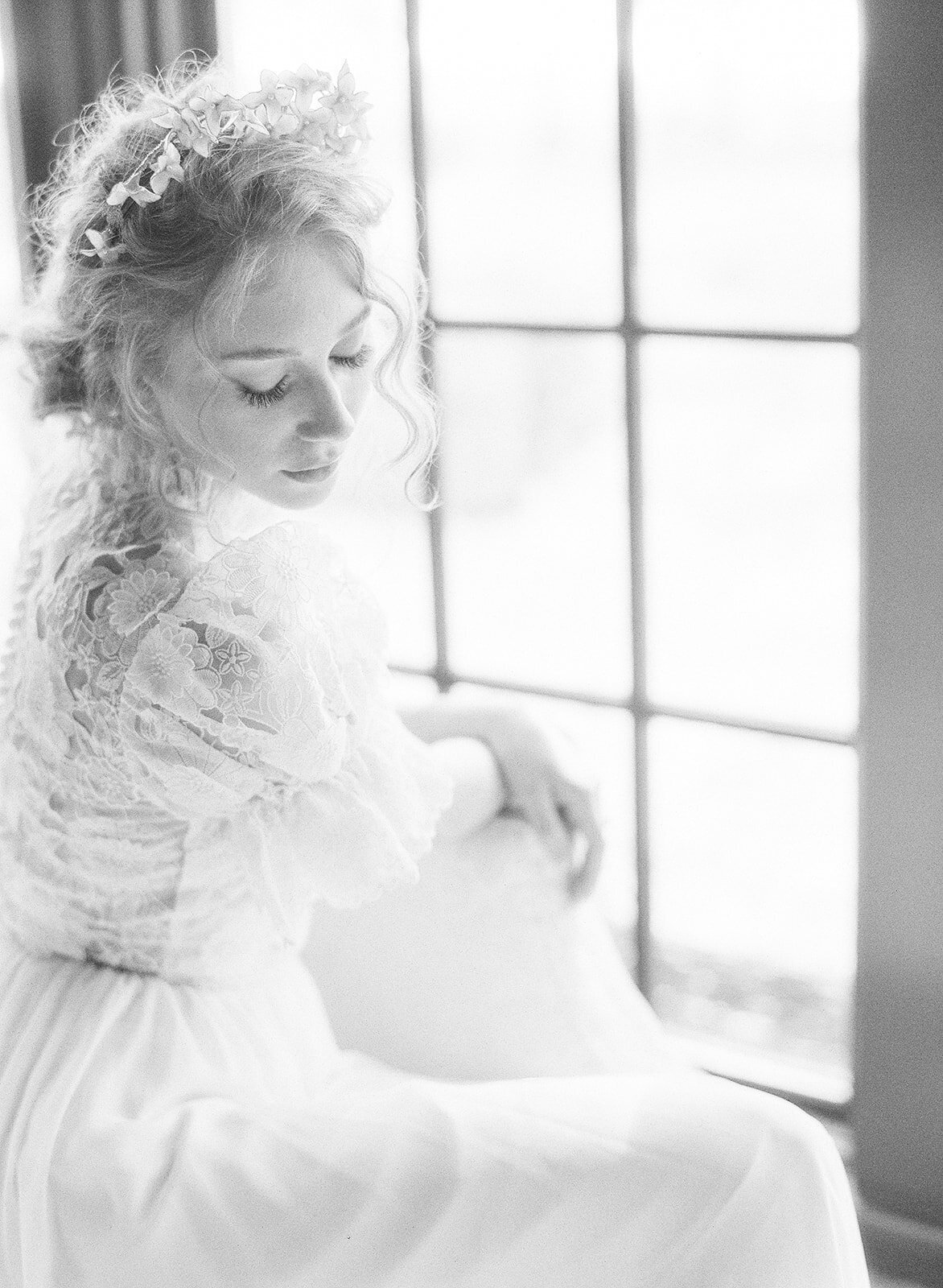 Black and white photograph of a bride in a puff sleeve lace wedding dress by a window at her villa wedding photographed by Italy wedding photographer